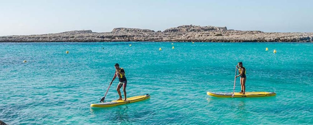 Conoced Menorca remando sobre una tabla de surf
